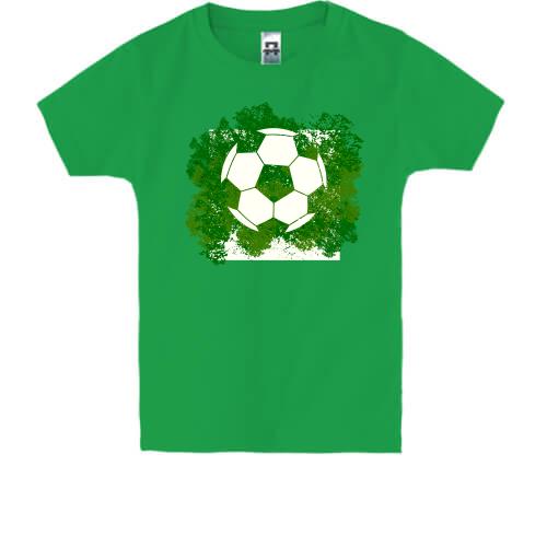 Дитяча футболка з футбольним м'ячем на фоні зелені